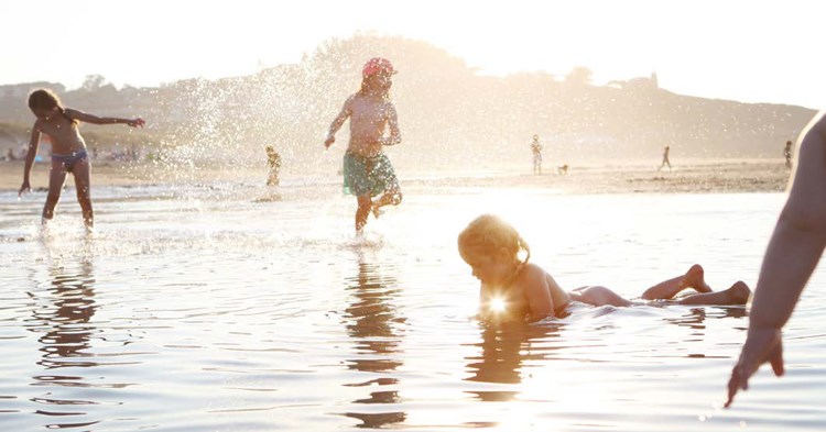 Barn som leker på stranden i San Vicent i de vattenhål som bildas efter tidvattnets sorti.