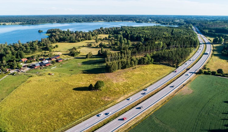 Flygfoto över motorväg med gröna fält.