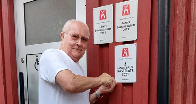 Leif Tellfjord monterar upp skylten "Länets bästa rastplats 2021"