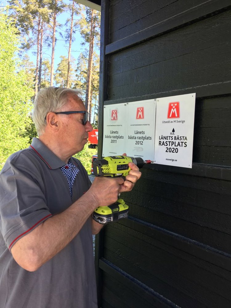 På bilden ses vägombud Hans Liljedahl som skruvar upp skylten Länets Bästa Rastplats 2020