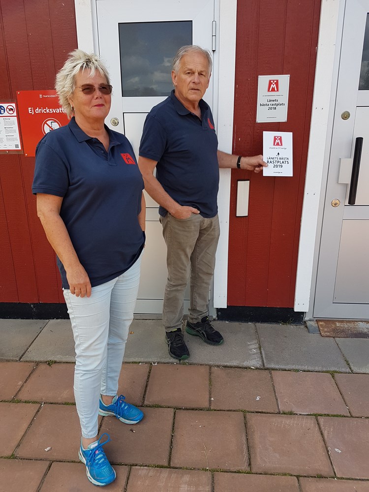 På bilden ses hur vägombud Jan-Erik Jönsson och Birgitta Karstensson sätter upp skylten "Länets bästa rastplats 2019" på rastplats Hänsjön nära Torsby