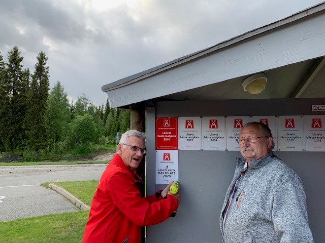 På bilden ses Christer Nyberg monterar skylten "Länets bästa rastplats 2020" tillsammans med skötselansvarige Kenneth Nyberg