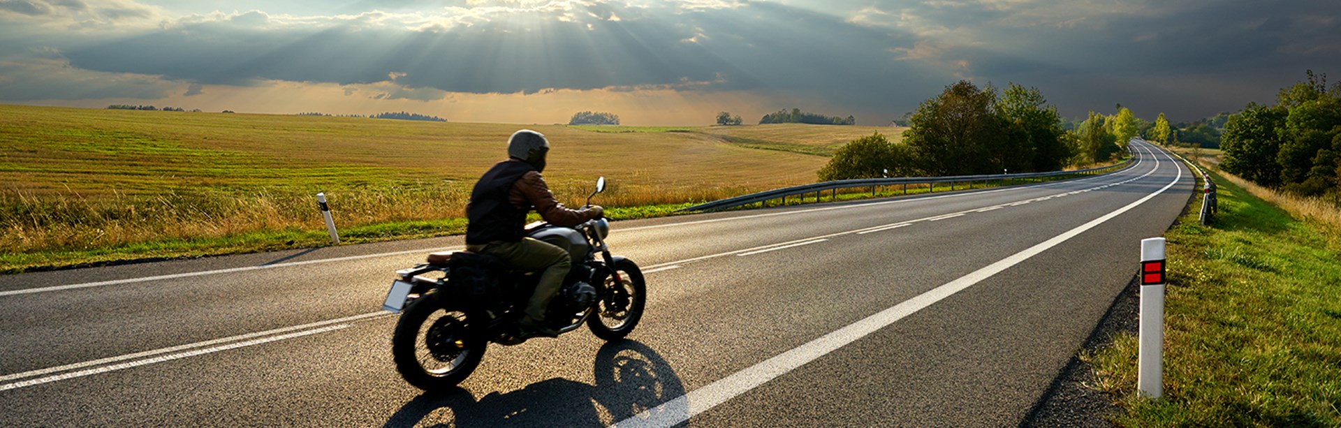 Motorcyklist kör på en lång en asfalterad väg