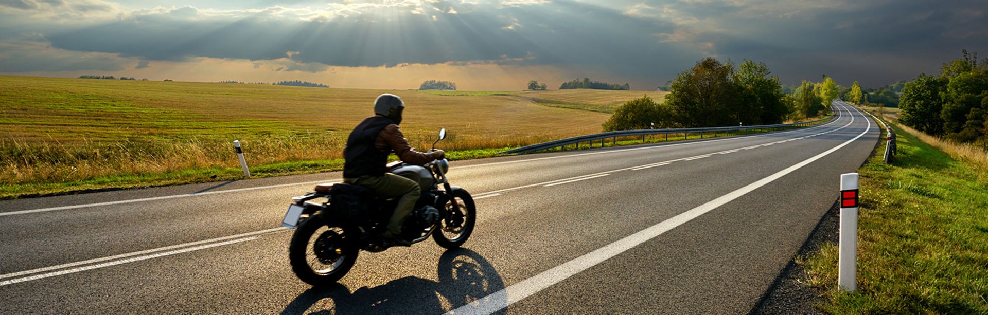 Motorcyklist kör på en lång en asfalterad väg