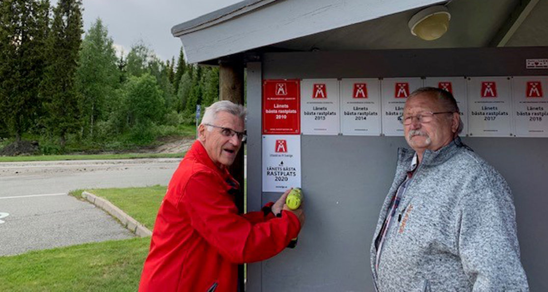 Christer Nyberg monterar skylten "Länets bästa rastplats 2020" tillsammans med skötselansvarige Kenneth Nyberg